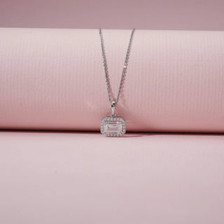 Close-up view of an emerald-cut diamond pendant in 14KT White Gold, featuring a diamond halo and a delicate chain.