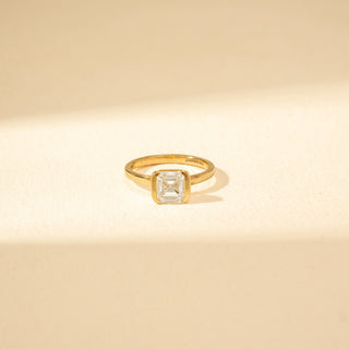 Close-up view of Emerald-Cut Solitaire Diamond Ring in 14KT Yellow Gold, featuring a bezel-set emerald-cut diamond.