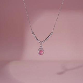 Front view of a pink gemstone and lab-grown diamond pendant necklace in 14KT White Gold, featuring a pear-shaped pink centre stone with a diamond halo. Captured against a pink backdrop, the elegant design radiates brilliance.