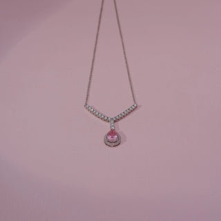Front view of a pink gemstone and lab-grown diamond pendant necklace in 14KT White Gold, featuring a pear-shaped pink centre stone with a diamond halo. Captured against a pink backdrop, the elegant design radiates brilliance.