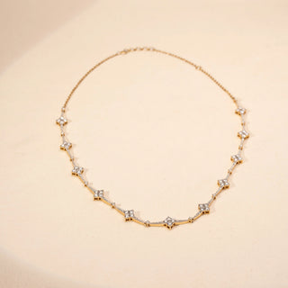 Top view of a star-inspired lab-grown diamond necklace in 14KT Yellow Gold, featuring bezel-set diamond star motifs linked by a delicate chain. Captured against a beige backdrop, the elegant design radiates subtle brilliance.