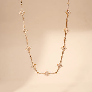 Front view of a star-inspired lab-grown diamond necklace in 14KT Yellow Gold, featuring bezel-set diamond star motifs linked by a delicate chain. Captured against a beige backdrop, the elegant design radiates subtle brilliance.