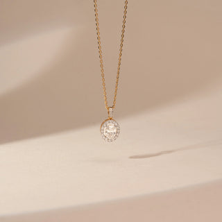 Front view of a 14KT Yellow Gold diamond pendant with an oval centre diamond, diamond-set halo and a diamond-set bail.
