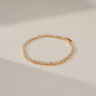 Top view of a yellow gold lab-grown diamond tennis bracelet featuring a continuous row of round brilliant diamonds in a classic four-prong setting, displayed on a neutral background.