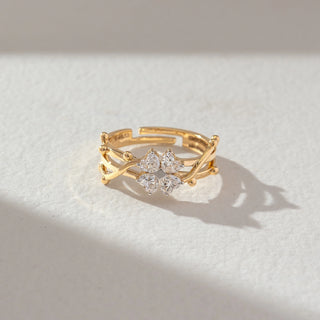 Top view of floral cluster diamond ring in yellow gold, featuring pear-shaped lab-grown diamonds arranged in a petal formation with an open layered band. Set on a soft neutral surface, it reflects graceful elegance.