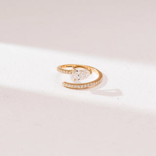 Front angle view of a 14KT yellow gold pear solitaire bypass diamond ring with a prong-set pear-shaped center stone and a curved pavé diamond band in an open wrap design.