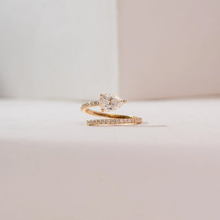 Front view of a 14KT yellow gold pear solitaire bypass diamond ring with a prong-set pear-shaped center stone and a pavé diamond band in a graceful open wrap design.