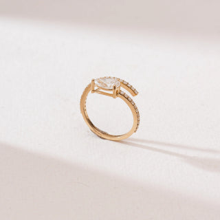 Side view of a 14KT yellow gold pear solitaire bypass diamond ring with a prong-set pear-shaped center stone and a curved pavé diamond band in an open wrap design.