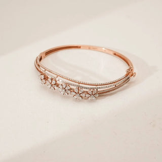 Top angled view of rose gold floral diamond bangle featuring clustered blossom motifs with pear-shaped petal diamonds and delicate pavé bands, displayed on a clean neutral background.