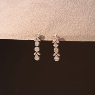 Side view of diamond drop earrings in 14 KT Yellow Gold, featuring cascading round and pear-shaped diamond clusters with marquise accents against a neutral backdrop.
