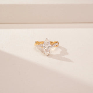 Close up view of a 14KT Yellow Gold diamond ring, featuring two marquise-cut diamonds and a diamond-set crossover band.