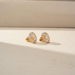 Side view of oval-cut diamond halo stud earrings in yellow gold, showcasing the elevated basket setting, sparkling halo detail, and secure screw-back posts in soft natural light.