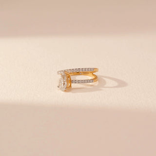 Side view of a 14KT yellow gold ring featuring a pear-cut diamond and round diamonds, set against a beige background.