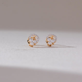 Front view of floral cluster diamond stud earrings in yellow gold, featuring round lab-grown diamonds arranged in a petal formation with a delicate diamond halo. Set on a soft neutral backdrop, they reflect graceful sparkle.