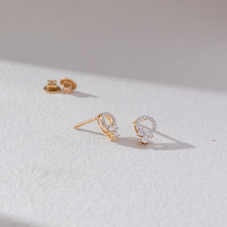 Angled front view of floral cluster diamond stud earrings in yellow gold, featuring round lab-grown diamonds in a petal cluster with halo detail and visible screw back. Set on a soft neutral surface, it reflects delicate brilliance.