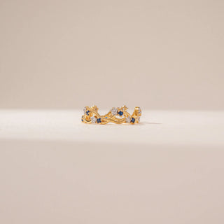 Front view of a blue sapphire and diamond ring in 14KT Yellow Gold, featuring an intertwined vine band against a beige backdrop.