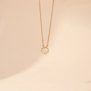 Front view of a 14KT yellow gold necklace featuring a round-cut diamond pendant, set against a beige background.