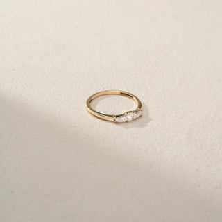 Top view of a tapered baguette diamond ring in 14 KT Yellow Gold, featuring a central emerald-cut lab-grown diamond flanked by tapered baguette side diamonds, displayed against a beige backdrop.
