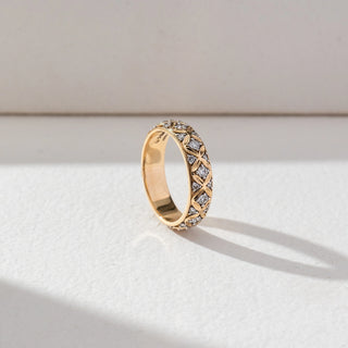 Side view of Patterned Diamond Band Ring in 14KT Yellow Gold, featuring round lab grown diamonds set within an intricate lattice design. Set on a beige backdrop, the band highlights texture and refined craftsmanship.
