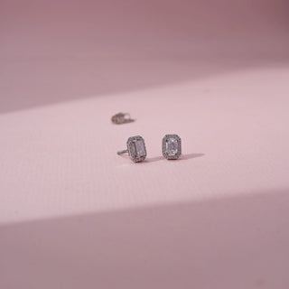 Angled view of emerald-cut lab-grown diamond halo stud earrings in 18 KT rose gold, featuring emerald-cut centre diamonds surrounded by octagonal pavé-set diamond halos in a timeless elegant design.