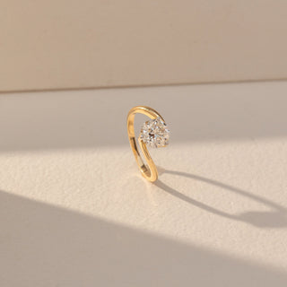 Side view of Round Solitaire Diamond Ring in 14KT Yellow Gold, featuring a centred round lab grown diamond in prong setting with a twisted band. Set on a beige backdrop, the design highlights structure and elegance.
