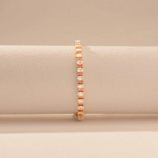 Front view of a 14KT dual gold bracelet featuring oval-cut diamonds, set against a beige background.
