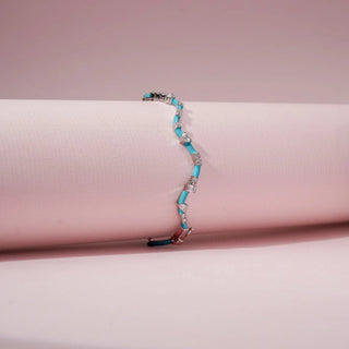 Angled view of a turquoise enamel bracelet in 14KT White Gold, featuring alternating diamond clusters and curved links against a pink backdrop.
