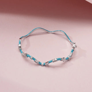 Top view of a turquoise enamel bracelet in 14KT White Gold, featuring alternating diamond clusters and curved links against a pink backdrop.