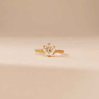 Front view of a 14KT Yellow Gold diamond ring with a round centre diamond, six-prong setting and diamond-set shoulders.