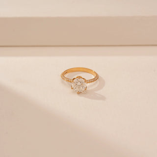 Close-up view of a 14KT Yellow Gold diamond ring with a round centre diamond, six-prong setting and diamond-set shoulders.