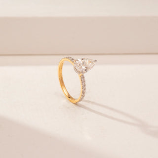 Angled view of a 14KT Yellow Gold diamond ring, featuring pear and round diamonds with a diamond-set band.