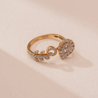 Top view of Reia’s 14 KT Yellow Gold Artisan Spiral Diamond Cocktail Ring. A pear-shaped motif and leaf-like bypass band, pavé-set with diamonds, wrap across a soft pink surface.
