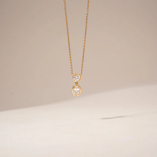Front view of a two-stone diamond pendant in 14KT Yellow Gold, featuring round and oval bezel-set diamonds.