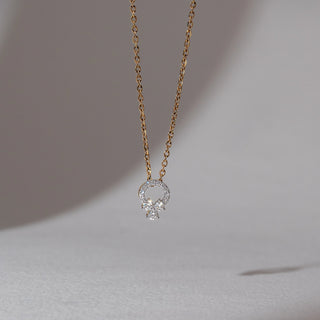 Front view of diamond pendant necklace in yellow gold, featuring a circular halo of round lab-grown diamonds with a floral cluster drop. Set against a soft neutral backdrop, it reflects subtle brilliance.