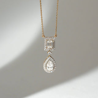 Front view of Dual Drop Diamond Pendant Necklace in 14KT Yellow Gold, featuring an emerald-cut halo top with a pear-shaped lab grown diamond drop below. Set on a neutral backdrop, the design highlights layered brilliance and elegance.
