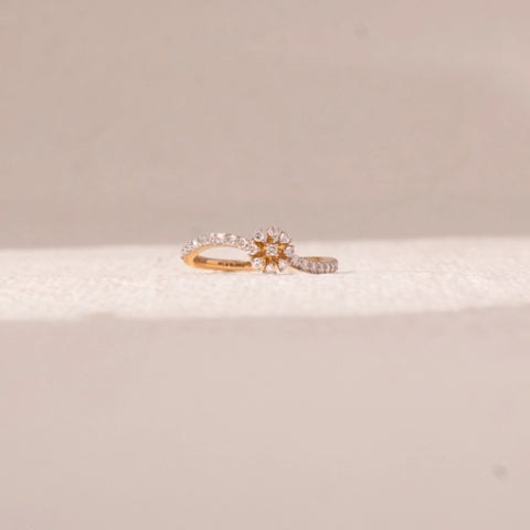 Front view of floral curve diamond ring in yellow gold, featuring a central flower cluster with round lab-grown diamonds and a split pavé band. Placed on a soft beige surface, the design reflects graceful brilliance.