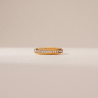 Front view of a diamond band ring in 14KT Yellow Gold, featuring a row of round diamonds between polished gold borders against a beige backdrop.