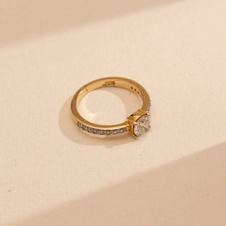 Top-down view of Reia’s 14 KT Yellow Gold Sparkling Solitaire Gold Diamond Ring. It highlights the brilliant central solitaire and the shimmering diamond-set band on a clean, cream backdrop.