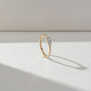 Side view of Baguette Diamond Band Ring in 14KT Yellow Gold, featuring a row of baguette-cut lab grown diamonds in prong setting. Set on a beige backdrop, the design highlights structure and clean elegance.
