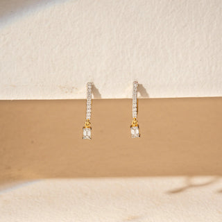 Front view of 14KT Yellow Gold drop earrings featuring emerald-cut diamonds, pavé-set bars and delicate dangling accents.