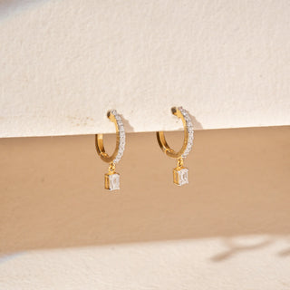 Side view of 14KT Yellow Gold drop earrings featuring emerald-cut diamonds, pavé-set bars and delicate dangling accents.
