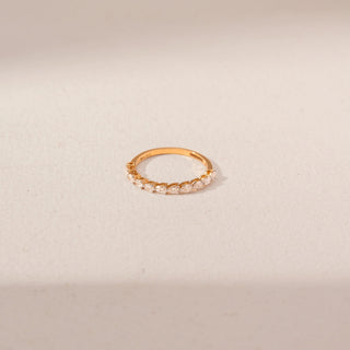 Top view of diamond band ring in 14KT Yellow Gold, featuring alternating pear-shaped diamonds. Captured against a beige backdrop.