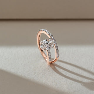 Side angled view of solitaire diamond ring in rose gold, featuring a large oval lab-grown diamond set on a curved dual-band with round diamond accents. Set on a soft neutral backdrop, it highlights brilliance and modern elegance.