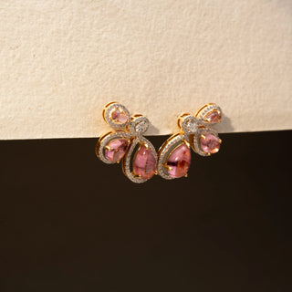 Side view of pink gemstone stud earrings in 14 KT Yellow Gold, featuring pear-shaped pink stones accented with halo-set diamonds in a floral-inspired arrangement against a neutral backdrop.
