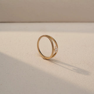 Angled view of a Trio Diamond Cluster Ring in 14KT Yellow Gold, featuring three round lab-grown diamonds in a floral cluster on a double-band design. Captured against a beige backdrop with soft shadow.