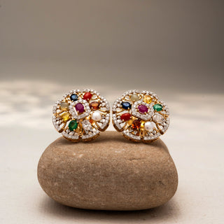 Front view of floral diamond stud earrings in 14 KT Yellow Gold, featuring multicolour gemstones, pearl accents, and pavé-set circular motifs, displayed on a textured stone surface.
