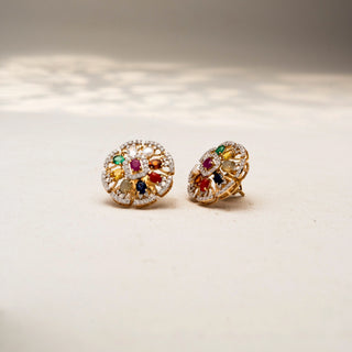 Angled view of floral diamond stud earrings in 14 KT Yellow Gold, featuring multicolour gemstones, pearl accents, and pavé-set circular motifs, displayed on a textured stone surface.
