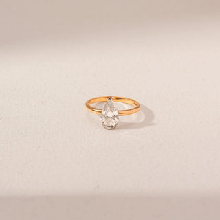 Top view of Pear Diamond Solitaire Ring in 14KT Yellow Gold, featuring a pear-shaped diamond. Captured against a beige backdrop.