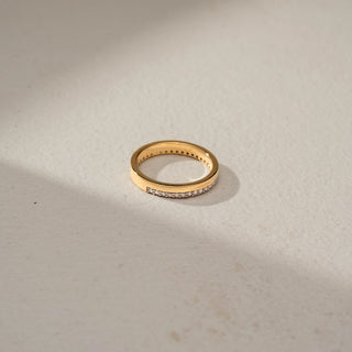 Top view of a diamond wedding band in 14 KT Yellow Gold, featuring a row of round lab-grown diamonds set within a sleek channel-style design, displayed against a beige backdrop.