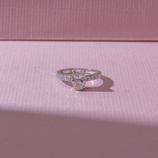 Top view of an oval diamond engagement ring in white gold, featuring a centred oval-cut diamond with pavé-set bands. Captured on a soft pink backdrop, highlighting radiant elegance and sparkle.
